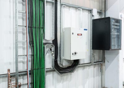 Trecho de infraestrutura elétrica e de rede com cabos identificados, presos e encaminhados em calhas dentro do equipamento.