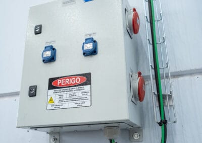 Painel de distribuição com tomadas industriais Pellegrin, rotulagem de circuitos e placa de advertência de perigo elétrico.