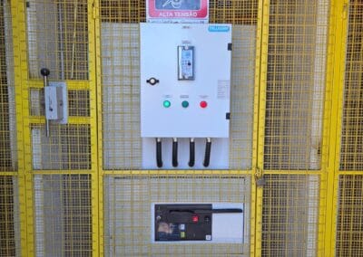 Quadro elétrico protegido por gaiola ou grade pintada em amarelo de alerta.