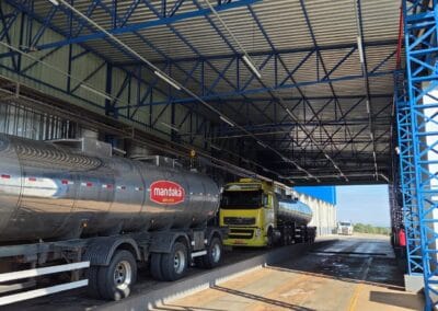 Frota de caminhões-tanque Mandaká estacionada sob cobertura em pátio logístico.