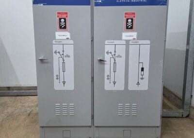 Painéis de alta tensão com diagramas unifilares na parede e piso com tapete isolante escuro.